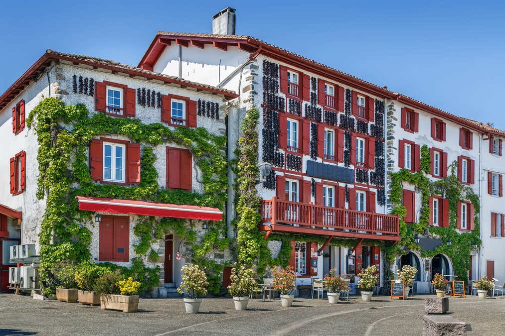 ville-espelette Façade d'une maison d'Espelette reconnaissable avec les nombreux piments qui y sont accrochés